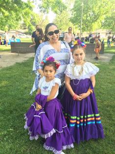 2 students in authentic folklore dress and an adult women standing by them. 